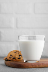 glass of milk and chocolate chip cookies with white brick wall as background