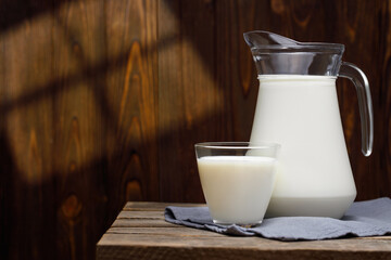 milk in glass and jug on wooden table