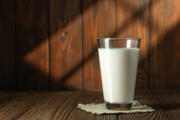 milk in glass on wooden table with sun rays