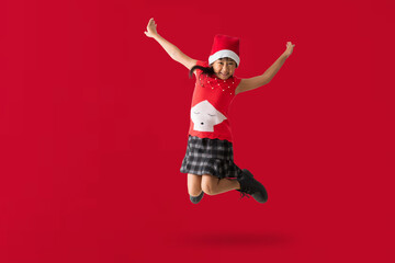 Happy smiling Asian child girl with wearing a red Christmas costume and Santa Claus hat, Celebration dancing and jumping have fun full body portrait, isolated on red background