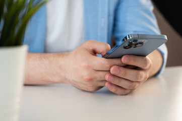 Close up cropped view male hands holding smartphone seated at table, spend time use e-date services for singles, mobile app usage, young gen and modern wireless tech, gadget overuse concept