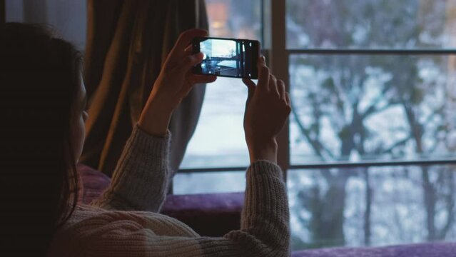 Mobile photography. Smartphone camera. Digital leisure. Young girl taking pictures of beautiful landscape scenery in window at home with cell.