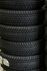 Sale of car tires for sale in the store. Many new winter tires lie horizontally. There is space for text