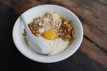 chicken porridge with fresh egg as topping with wooden background