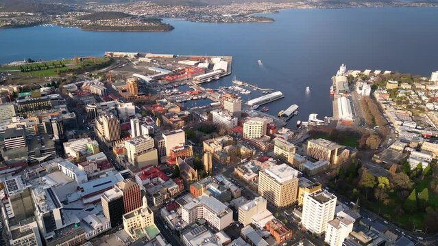 Hobart, Australia: Aerial drone footage of the Hobart central business district and Wharf harbor in Tasmania main city on a sunny day. Shot with a backward and tilt up motion