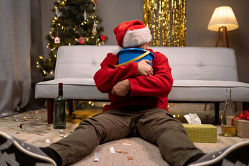 Bearded man has a severe stomach ache, sits near couch with bucket near the Christmas tree, alone...