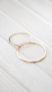 Two gold wedding rings lie on a white wooden table close-up. Rotating the camera around two gold wedding rings. 3D render.