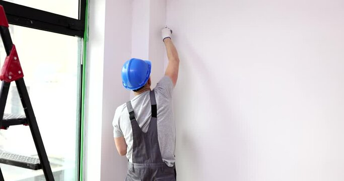 Master paints corner wall with brush white. Wall repair and painting