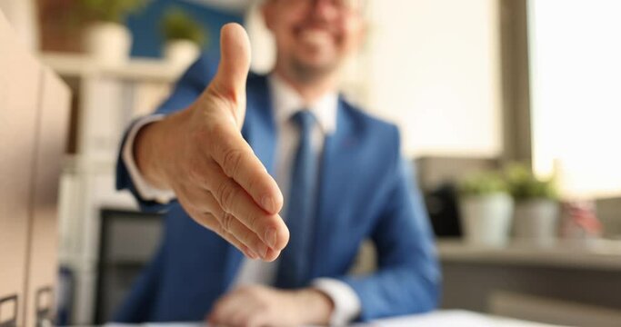 Professional businessman HR consultant extends hand in front of camera for handshake and greeting. Offers of cooperation and welcome to cooperation
