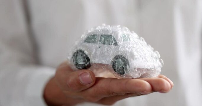 Toy car wrapped in transparent bubble wrap. Auto insurance guarantee protection