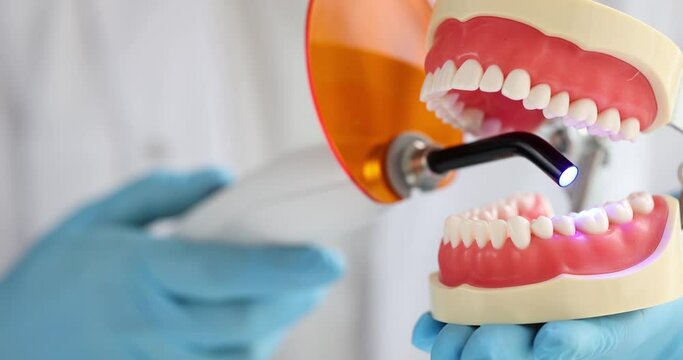 Dentist photopolymer lamp with luminous blue lamp. Dentist treats dental prosthetics puts fillings treats gum caries