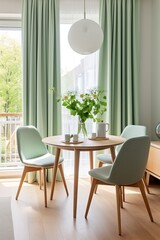 Mint color chairs at a round wooden dining table against the window dressed with light green and white curtains. Scandinavian interior design