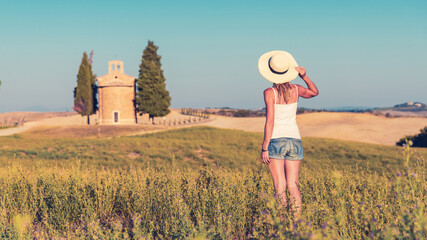 Traveler female tourist looking at famous church and cypress in Tuscany,  Italy