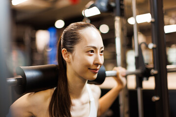 マルチトレーナーマシンで運動する若いアジアの女性 - obrazy, fototapety, plakaty