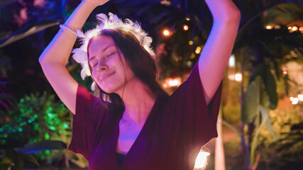 young woman dances in the evening against the backdrop of colorful garlands