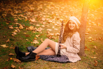 Young attractive girl with clarinet, ebony in fall park