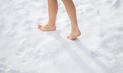Beautiful women's feet walk barefoot on freshly fallen snow. Healthy lifestyle concept. Temper...