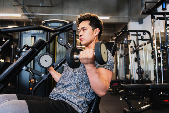 ダンベルでの若いアジア人の訓練
