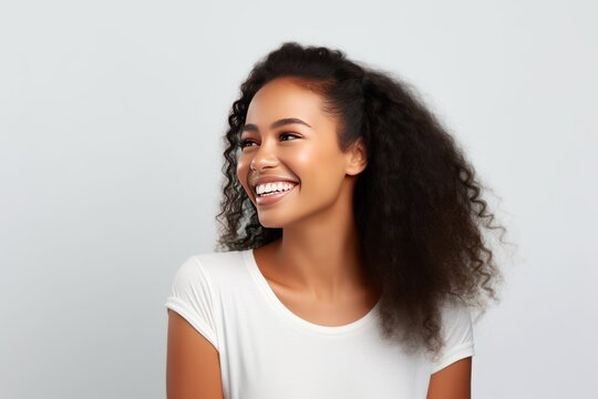 Closeup photo portrait of a beautiful young african american model woman smiling with clean teeth. Used for a dental ad. Isolated on light background.