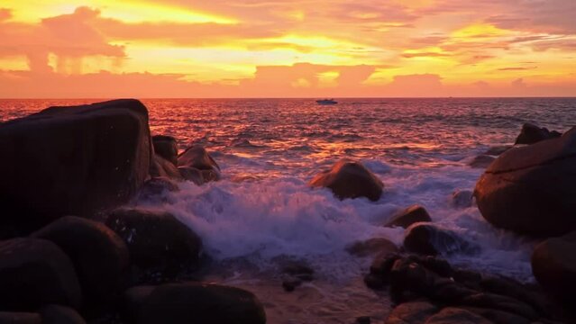 .slow motion scene of waves hitting the rocks at bright yellow sunset..Waves lapping on the rocky beach in the stunning sunset..slowly waves lapping on the rocky beach in a white foam wave..