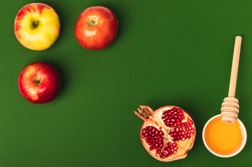Honey, three apples and half a pomegranate on a green background. Rosh Hashanah holiday. Jewish New...