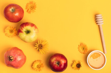 Honey, three apples, pomegranate and yellow flowers on a yellow background. Rosh Hashanah holiday. Jewish New Year.