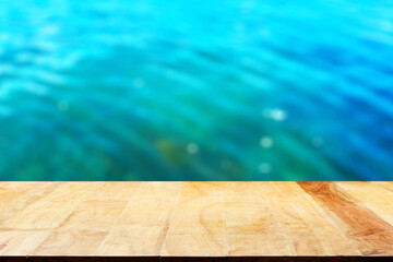 Empty wooden table top and blurred swimming pool background.