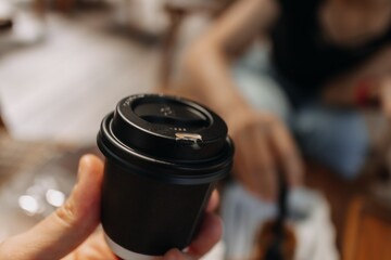 Fototapeta na wymiar Presenting black cup of hot coffee in a cafe.