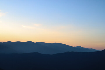 dawn in the mountains dark silhouettes of mountain ranges against the background of the orange sky