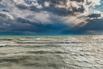 The sun's rays break through thunderclouds in Issyk-Kul. Storm on the lake.