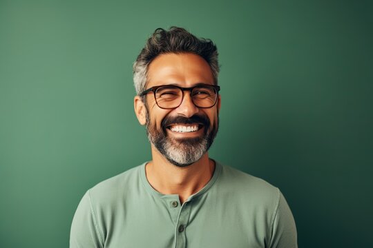 Portrait of a handsome mature man wearing glasses and smiling while standing against green background