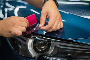 The master in the car service applies an armor film to the car. 
