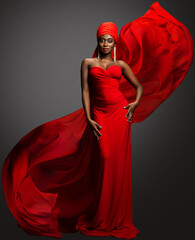 Fashion Woman in Red Dress and Hijab. African Model in Evening long Gown with flowing Silk Fabric...