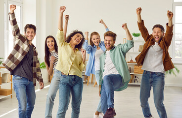 Funny happy overjoyed group of friends celebrating success holding hands up and looking at the...