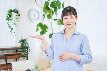 手で案内する自宅で仕事をする女性　立ちポーズ