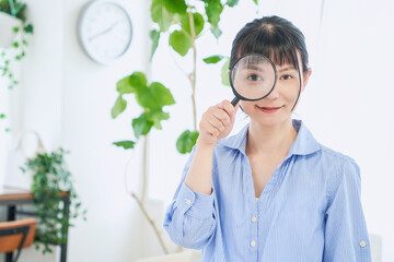 虫眼鏡を持つ自宅で仕事をする女性　立ちポーズ