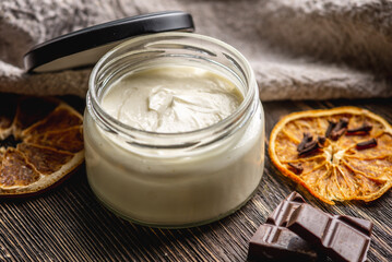 Natural fragrant cream or butter for body in a clear glass jar on a wooden background. Concept of organic cosmetics and skin care