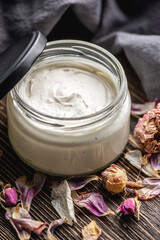 Natural fragrant cream or butter for body in a clear glass jar on a wooden background. Concept of organic cosmetics and skin care