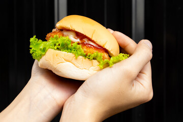 woman holds tasty burger in two hands.