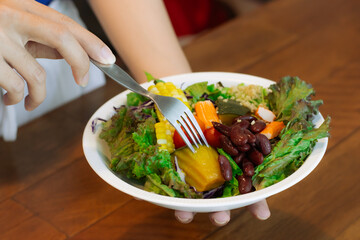 Eating mixed salad fresh green vegetable in white bowl.