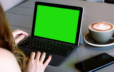 Close up of businesswoman using laptop computer with mock up green screen chroma key display in cafe.