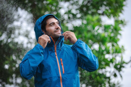 man in a raincoat in the rain in a rainy day in the park, the concept of the rainy season