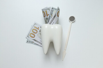 Decorative tooth and money on white background, top view