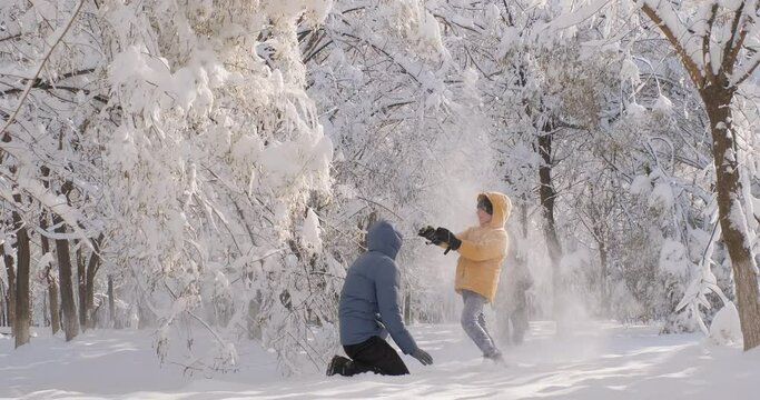 Family enjoy winter. Father with kids play with snow in a beautiful park on a sunny winter day, having fun walking outdoors in cold winter, winter holidays