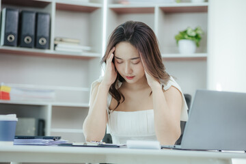 Obraz na płótnie Canvas Asian woman stressed while working in the office Asian business woman who is tired from work feeling sick at work