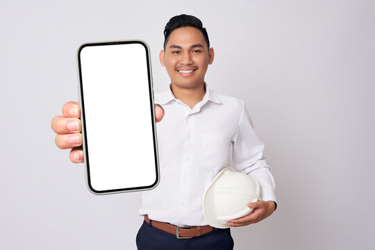 Professional engineer young Asian men wearing formal shirts and protective construction helmet holding big smartphone with blank screen while smiling expressions isolated on white background