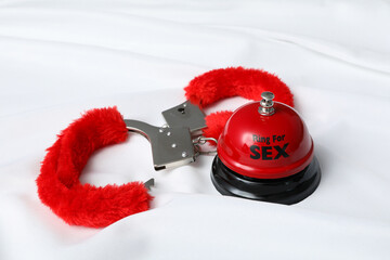 Red, fluffy handcuffs for sex play on a white background.