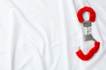 Red, fluffy handcuffs for sex play on a white background.
