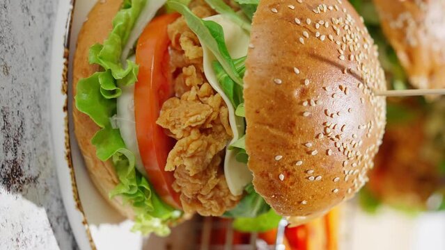 Crispy, breaded chicken double burgers with vegetables and drink, served with sweet potatoes