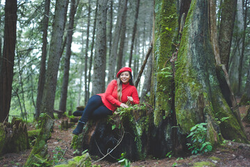 Woman with positive attitude on a mossy tree stump in the middle of the forest.